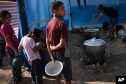 Palestinian children wait for a food distribution in a displaced tent camp, in Khan Younis, southern Gaza Strip, Oct. 25, 2023.