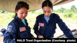 ໃນລາວ ນາງນາຟອນ ໂທຈັນ, ເຈົ້າໜ້າທີ່ຄຸ້ມຄອງຂອງ HALO ກຳລັງກຳກັບນຳພະນັກງານເກັບກູ້ລະເບີດຢູ່ເຂດລະເບີດຝັງດິນ ໃກ້ກັບບ້ານກາລອງເໜືອ ແຂວງສະຫວັນນະເຂດ.