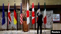 資料照：一名男子在日本東京舉行七國集團外交部長會議期間整理成員的旗幟。（2023年11月8日）