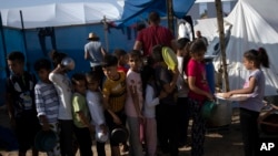 Children wait in line for a food distribution in a displaced tent camp, in Khan Younis, southern Gaza Strip, Oct. 25, 2023.