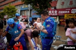 由志愿者组成的中国民间救援队蓝天救援队成员在河南郑州对洪灾灾民实行救援。（2021年7月22日）