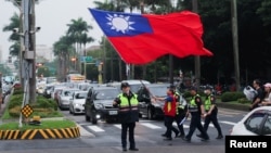 台灣警察護送一名舉著台灣旗幟的男子走過台北街頭。 （2024年5月24日）
