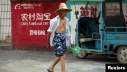 资料照：2015年7月20日中国浙江桐庐农民走过淘宝广告墙