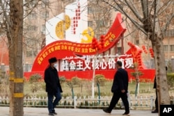 新疆和田居民走過街頭豎立的社會主義核心價值觀的宣傳牌。（2021年3月22日）