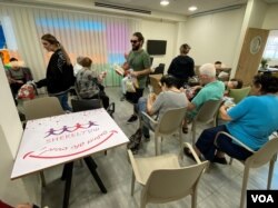 一位叫Iris 的以色列婦女，長期在固定時間到SHEKEL Sigaliyot 日照中心當志願者，但因戰爭需照顧無法上學的孩子，而無法來當志願者，10月25日她託人送來一大箱零食和一大箱各式桌上遊戲給受照顧老人，讓這些如孩子般的老人特別開心。(美國之音賴素芬)