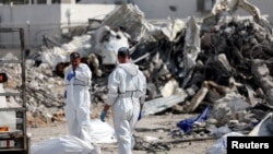 以色列救援人員在南部的斯德羅特市一個被進入以色列國土的哈馬斯武裝分子的警察局廢墟旁尋找死難者，那裡曾經展開槍戰。（2023年10月11日）