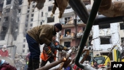 俄罗斯导弹袭击摧毁基辅中心的高楼后，工作人员修复楼外水管。(2024年1月3日)