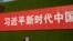 一名女子從北京街頭張貼的一條宣傳習近平新時代的標語下走過。 （2019年9月27日）