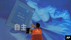 一名工人在上海舉辦的世界人工智能大會上檢視中國科技公司中科曙光展示的芯片和自主字樣的螢幕。 （2023年7月5日）