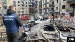 烏克蘭頓內茨克地區一棟被俄羅斯飛彈摧毀的居民樓房和附近受損的汽車。（2024年3月10日）