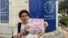 2023年4月下旬，杨泽伟（网名乔鑫鑫）同友人一道在欧盟驻老挝外交机构门外举牌呼吁拆除网络防火墙。（乔鑫鑫提供照片）