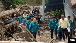 ປະທານາທິບໍດີເກົາຫຼີໃຕ້ ທ່ານຢຸນ ຊຸກ ໂຢລ (ກາງ), ຍ່າງຜ່ານກອງຕົ້ນໄມ້ທີ່ຫັກລົ້ມ ຢູ່ໃນໝູ່ບ້ານ ເຊິ່ງເປັນຂົງເຂດທີ່ມີບ້ານເຮືອນຫຼາຍກວ່ານຶ່ງສ່ວນສາມ ຖືກທໍາລາຍດ້ວຍສະພາບດິນເຈື່ອນ ແລະສອງຄົນຍັງຄົງຫາຍສາບສູນ, ໃນເມືອງເຢຊິນ, ວັນທີ 17 ກໍລະກົດ 2023.