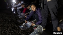 资料照片: 2023年4月3日美国得克萨斯州弗龙顿: 一名从墨西哥格兰德河偷渡进入美国的中国妇女将自己的物品放入塑料袋