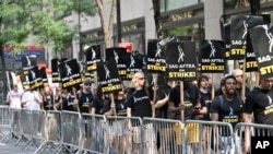 美國影視演員協會(SAG-AFTRA)2023年7月17日在紐約洛克斐勒中心的全國廣播公司(NBC)外舉著標語遊行。（美聯社圖片）