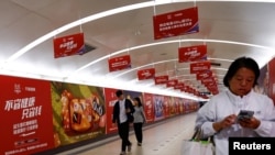 北京地铁乘客走过阿里巴巴为11月11日光棍节大促销所作广告的通道。（2023年10月26日）
