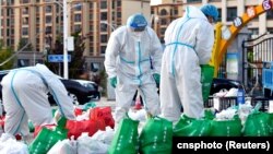 西藏拉薩街頭身穿防護服的大白為被封在家中的居民整理食品袋。 （2022年9月29日）