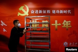 一名工作人員在北京一家酒店的中共二十大新聞中心走過宣傳中國領導人習近平的標語。 （2022年10月19日）