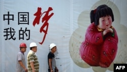 幾名中國工人走過北京街頭張貼的中國夢宣傳畫。（2013年9月2日）