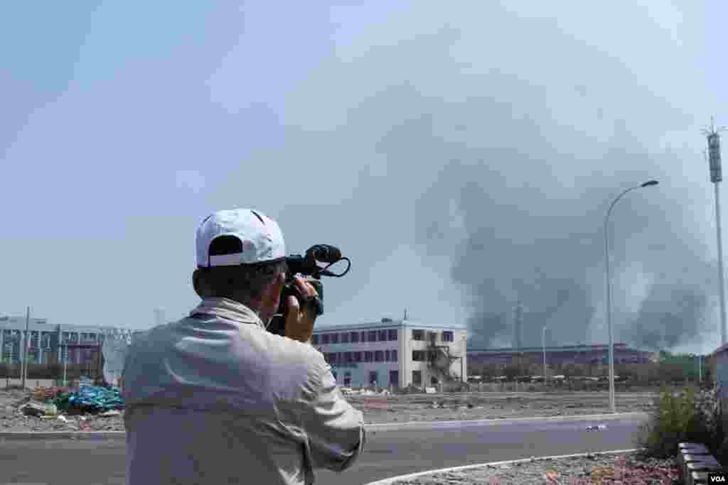 天津爆炸事故现场，核心爆炸区周围多座居民楼窗户被震碎，高速公路桥梁受损，多辆大货车被炸翻，小汽车起火或被砸，多名当地居民仍逗留在事故现场。（美国之音记者东方拍摄）