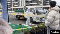 身穿防護服的警察站在運送綠色鐵絲圍欄的汽車旁。 （2022年4月15日）