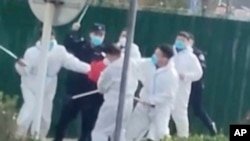 中國河南鄭州富士康代工廠裡身穿防護服的警察和保安毆打參加示威活動的工人。(2022年11月23日)