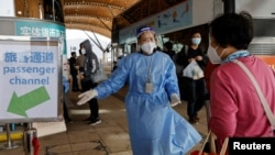 一名旅客在港珠澳大桥外与一名身穿防护服的工作人员交谈。（2022年12月23日）