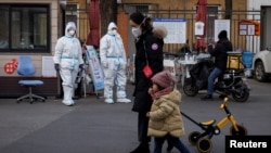 身穿防護服的大白站在北京一居民小區的大門處執勤。 （2022年12月7日）