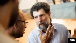 ແຟ້ມ-ເອກະສານພາບທີ່ບໍ່ຮູ້ມື້ຖ່າຍ ໄດ້ຮັບການເຜີຍແຜ່ໃນວັນທີ 15 ຕຸລາ 2021 ໂດຍສູນກາງດ້ານວັດທະນະທໍາ ອານາໂດລູ, ໄດ້ສະແດງໃຫ້ເຫັນຜູ້ມີໃຈບຸນຊາວເທີກີເຊື້ອສາຍຝຣັ່ງ ທ່ານໂອສມານ ຄາວາລາ ກໍາລັງກ່າວສົນທະນາ ຢູ່ໃນງານແຫ່ງນຶ່ງ ໃນນະຄອນອິສຕັນບູລ. 