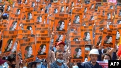 ແຟ້ມ-ຢູ່ໃນພາບທີ່ຖ່າຍເມື່ອວັນທີ 28 ກຸມພາ 2021, ຜູ້ປະທ້ວງພາກັນຍົກປ້າຍທີ່ມີພາບຂອງຜູ້ນໍາພົນລະເຮືອນ ທ່ານນາງ ອອງ ຊານ ຊູ ຈີ ໃນລະຫວ່າງການປະທ້ວງຕໍ່ຕ້ານການເຮັດລັດຖະປະຫານຂອງພວຫທະຫານ ໃນນະຄອນຫຼວງເນປີດໍ, ປະເທດມຽນມາ. 