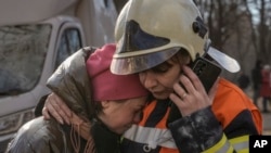 基輔一座居民樓遭轟炸被毀後，消防隊員在樓外安慰一名女子。(2022年3月15日)