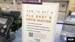 资料照片：华盛顿近郊马里兰州一家杂货店兼药店的柜台上说明如何接种流感疫苗和新冠疫苗的告示牌。(2022年10月31日)