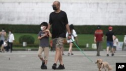 台北市民戴著口罩遛狗散步。 （2022年4月27日）