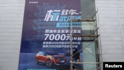 2020年8月9日，工人們在中國湖北省武漢市的一家經銷店張貼了政府補貼東風標致汽車的巨幅海報。（路透社）