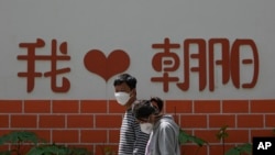 北京朝陽區兩個帶著口罩的居民去排隊做新冠核酸檢測。（2022年5月11日）