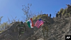 2022年11月30日，印度和美国陆军士兵举着各自国家的国旗，在印美联合演习期间跑上一座小山。 (美联社照片）