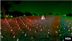 一名活動人士坐在華盛頓紀念碑附近擺放的國旗中，紀念在美國新冠肺炎大流行中喪生的180,000人。 (2020年08月27日)