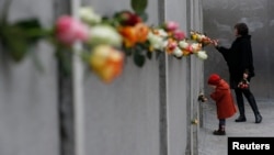 2014年11月9日柏林牆倒塌25週年: 母親和女兒在貝爾瑙爾大街柏林牆紀念館獻上玫瑰