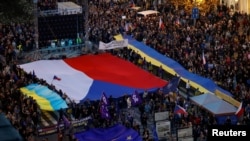 2022 年 10 月 30 日，在捷克共和国布拉格举行的亲政府和反战抗议集会上，示威者举着旗帜。 