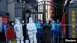 资料照片：“大白”站在北京东营房一个被封居民小区的大门口。(2022年10月22日)