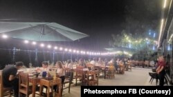 ພາບບັນຍາກາດຢູ່ທີ່ດ້ານນອກຂອງຮ້ານ ທີ່ຕິດກັບແຄມແມ່ນໍ້າຂອງໃນຍາມກາງຄືນ, ເຊິ່ງສາມາດແນມເຫັນຝັ່ງນະຄອນພະນົມ ຂອງປະເທດເພື່ອນບ້ານ.