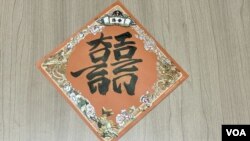 阿金以毛筆書寫的Hong Kong雙囍斗方揮春。(美國之音照片)