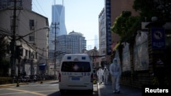 上海街头停着的120急救车旁走过身穿防护服的人。（2022年4月16日)