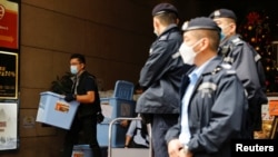 資料照：2021年12月29日，香港一名警察在搜查了《立場新聞》辦公室後收集了一箱證據。 （路透社）