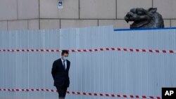 上海一家商場圍欄外走過一名戴著口罩的工作人員。 （2022年4月20日）