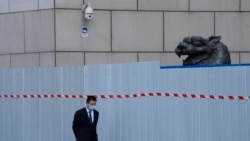 上海一家商場圍欄外走過一名戴著口罩的工作人員。 （2022年4月20日）