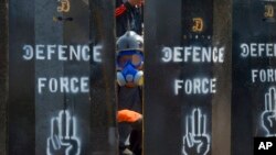 资料照片： 2021年3月11日，一名反政变抗议者从缅甸仰光设立的临时路障空隙中窥视。（美联社照片）