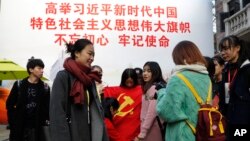 一群大学生手举中共党旗在写有“习近平语录”的宣传板前合影。（2017年11月19日）