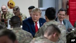 2019年11月28日星期四，特朗普总统在共和党参议员约翰·巴拉索陪同下共进晚餐时微笑。他在当天的感恩节突防阿富汗巴格拉姆空军基地。 （美联社照片）