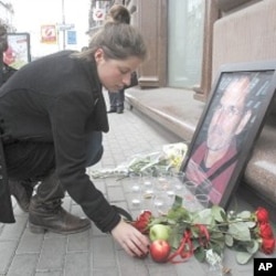 在莫斯科市中心，一位妇女把一个苹果放在一家苹果电脑商店外的乔布斯的画像边