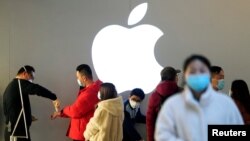 资料照：戴着口罩的人们排队等候测量体温进入一家上海的苹果商店。（2020年2月21日）